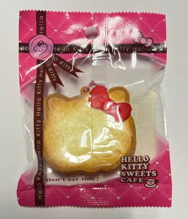 RARE Hello Kitty Sweets Cafe bread squishy shaped like a golden loaf with Hello Kitty details, packaged in original wrap with pink ball chain and red Sanrio authenticity sticker; vintage 1976–2010 collectible with possible age-related wear.