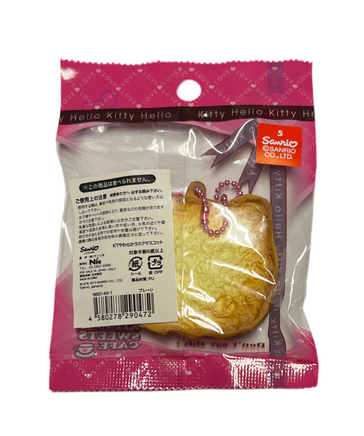 RARE Hello Kitty Sweets Cafe bread squishy shaped like a golden loaf with Hello Kitty details, packaged in original wrap with pink ball chain and red Sanrio authenticity sticker; vintage 1976–2010 collectible with possible age-related wear.