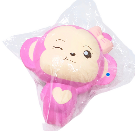 Plush monkey toy with pink bow in clear packaging on a white background