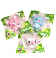 Three licensed I-Bloom Koala squishies in blue (KEN), gray (LUDLOW), and pink (BELLE), each with soft, rounded features and a super slow-rising texture. Displayed in original 2017 packaging, showcasing their collectible design and pastel colors.