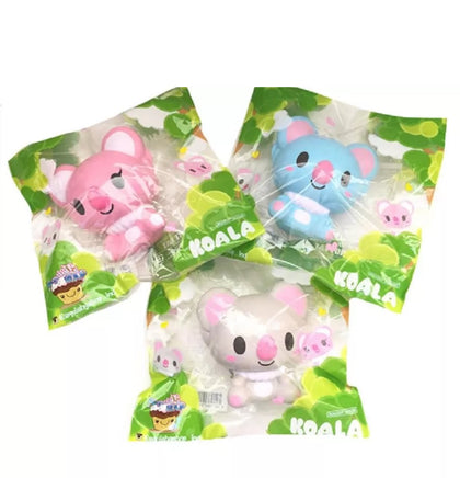 Three licensed I-Bloom Koala squishies in blue (KEN), gray (LUDLOW), and pink (BELLE), each with soft, rounded features and a super slow-rising texture. Displayed in original 2017 packaging, showcasing their collectible design and pastel colors.
