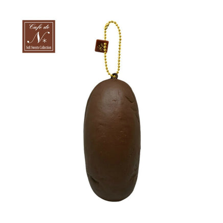 Cafe de N Bakery Koppe Pan squishy, realistic bread roll design measuring 5 by 2.5 inches, light golden-brown color with original 2017 packaging and product tag, soft slow-rising texture.
